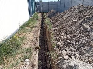 Keskeny közműárok épület mellett